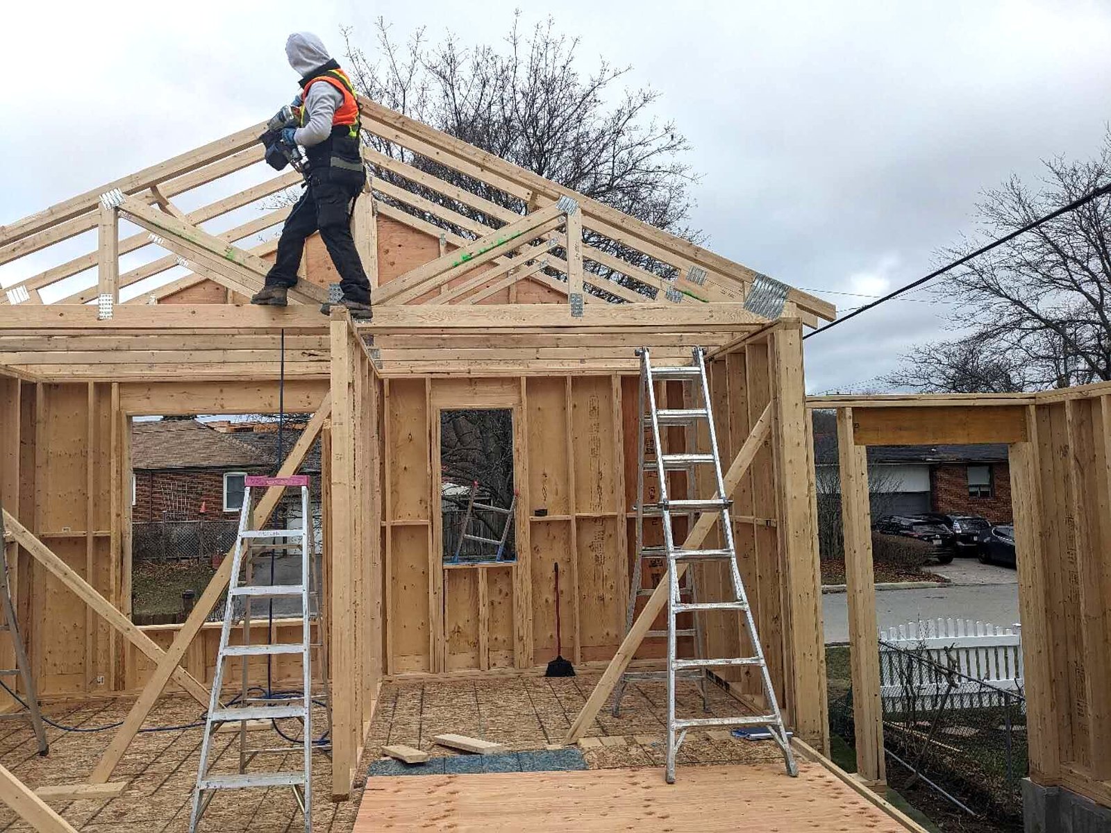Laneway house wall framing and trusses with a worker on the roof