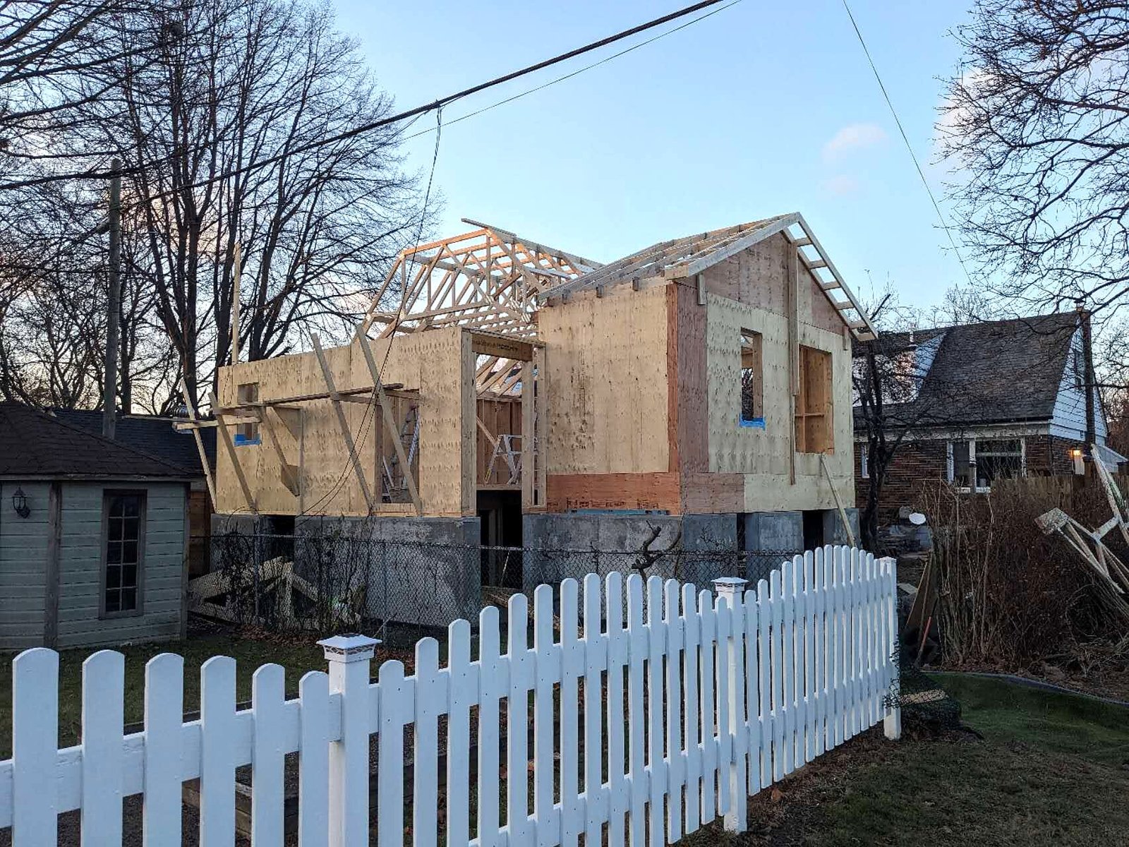 Laneway house framing seen behind a white picket fence