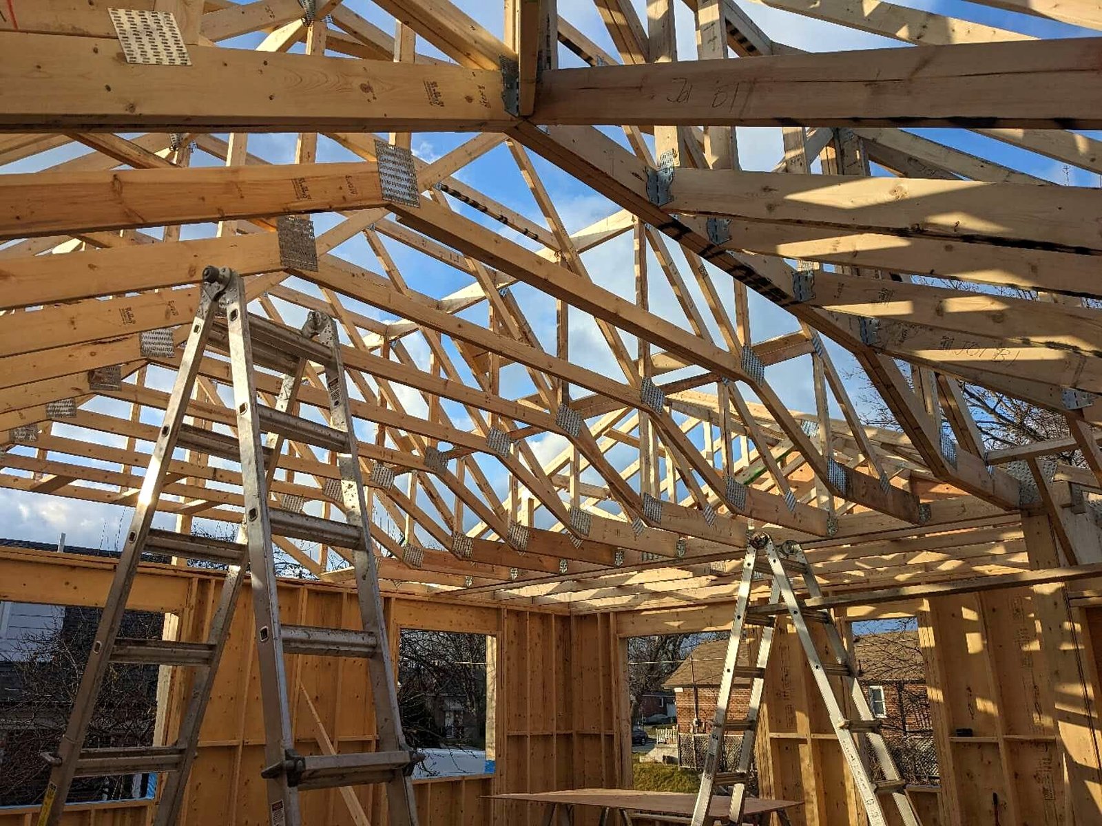 Roof truss framing inside a laneway house with ladders